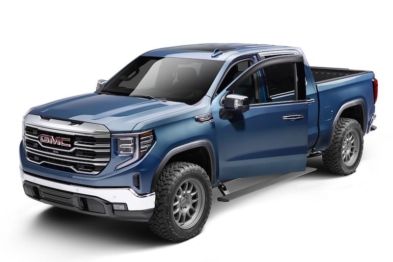 Blue GMC pickup with its AMP Research power step deployed and driver door open